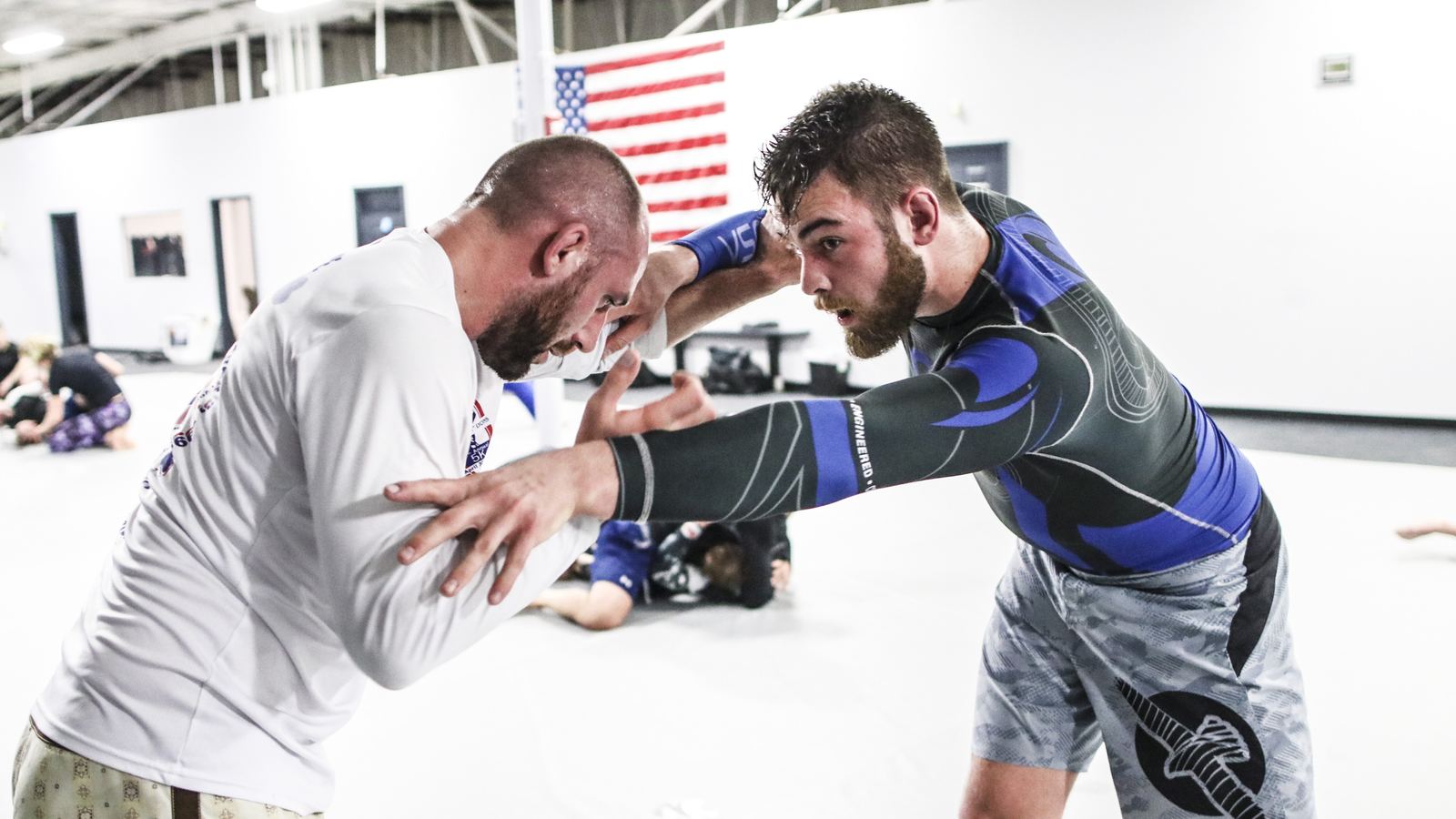 A coach in white framing against a partner's strike during a defense drill.